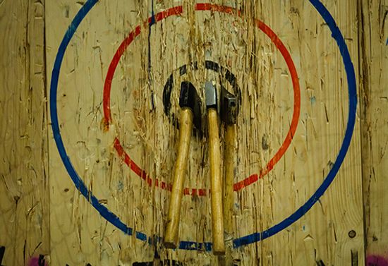 Two axes thrown into the bullseye of an axe board.