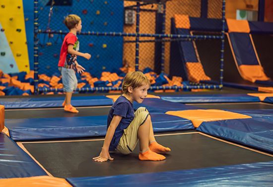 Children sitting and standing on an indoor trampoline.
