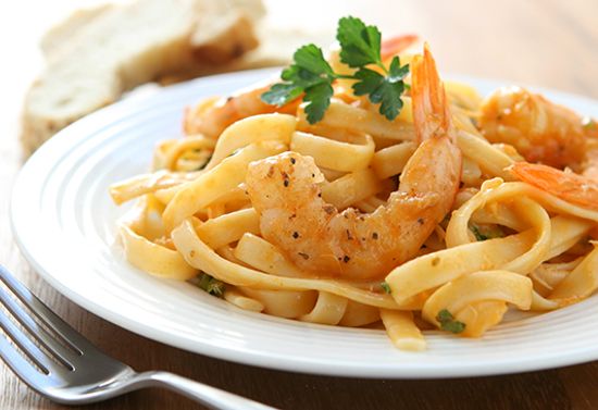 Noodle dish with shrimp, on a white plate.