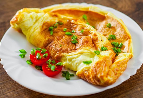 Omelet with sliced tomatoes on a white plate.