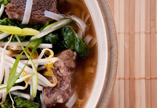 Pho soup in a white bowl.