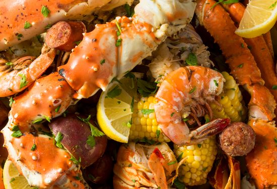 Plate of seafood boil, which includes crab, shrimp, corn, and lemons.