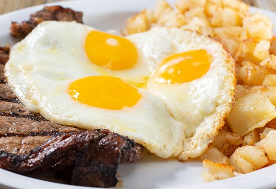 Plate of three eggs, steak, and potato wedges.