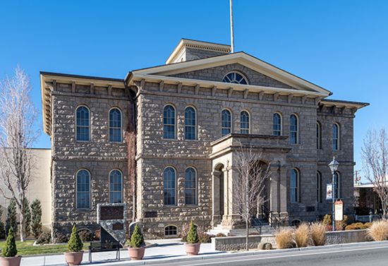 Large beige building with shrubbery.