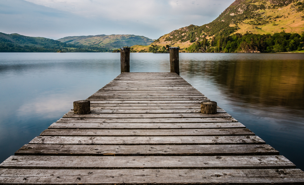 Dock leading into a body of water surrounded by mountains