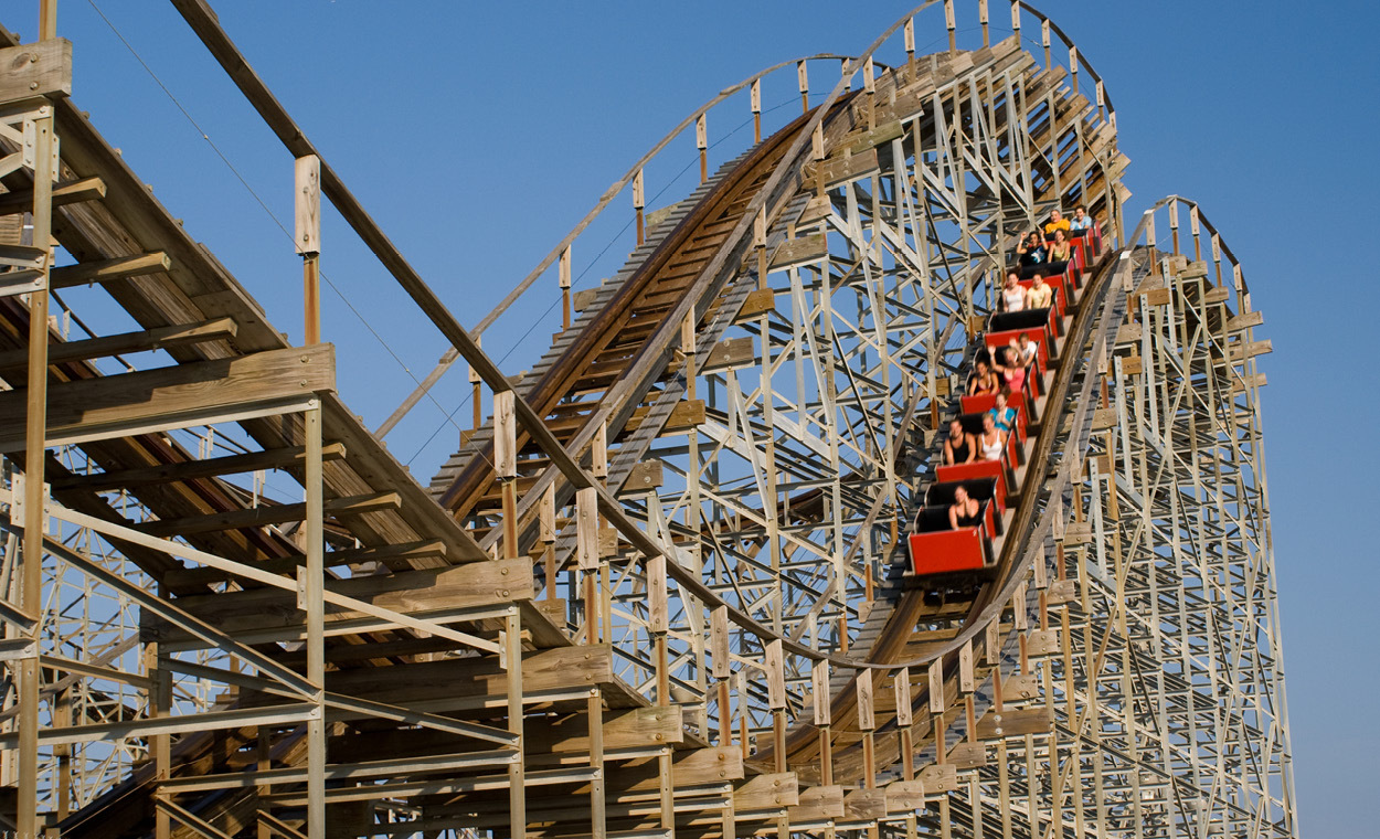 Rollercoaster track with red roller coaster speeding down.