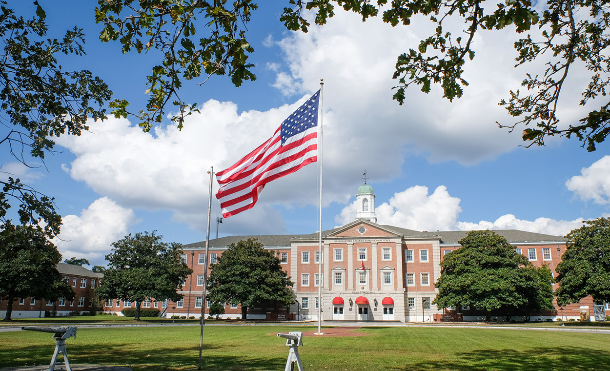 Large building with a green space and United States flag in front.