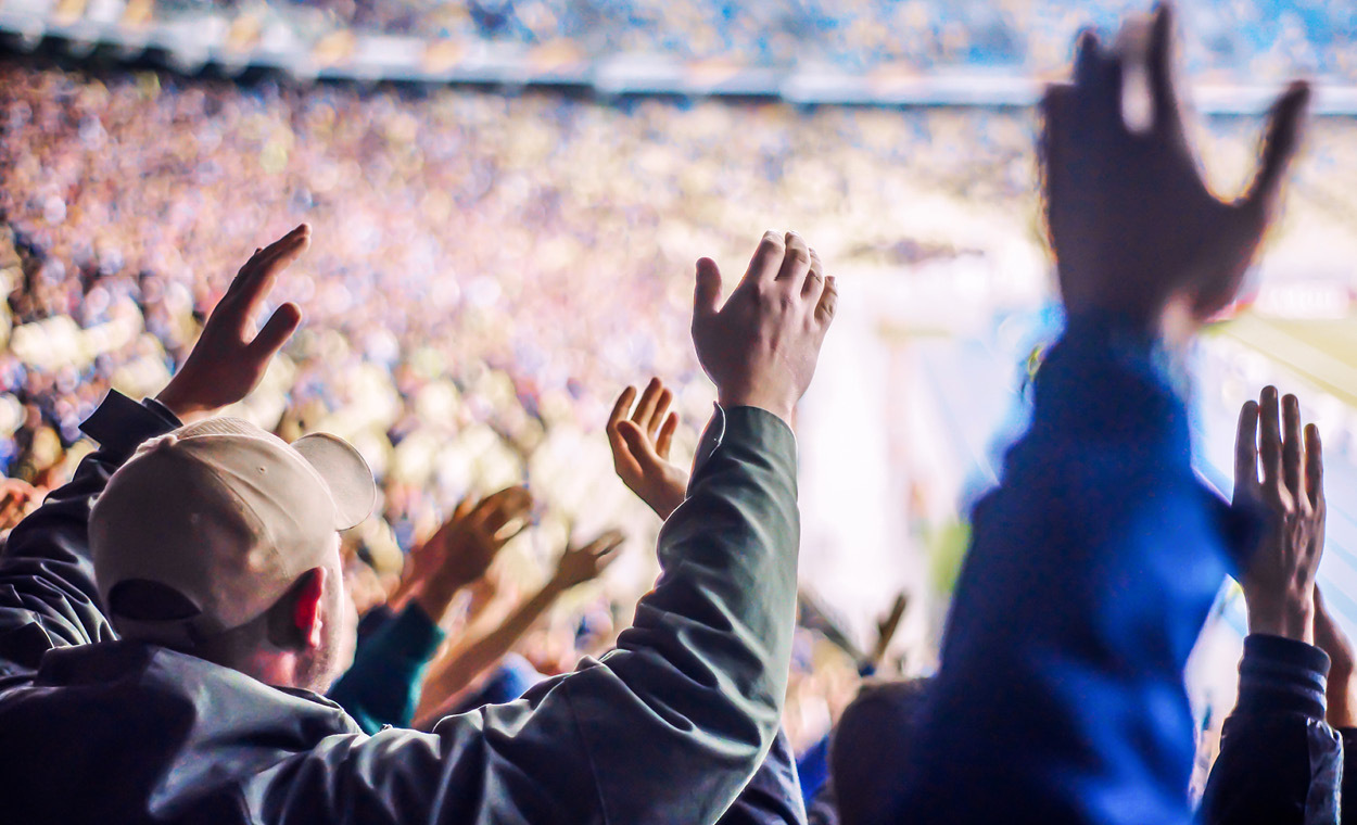People cheering with their hands in the air at a sporting event.