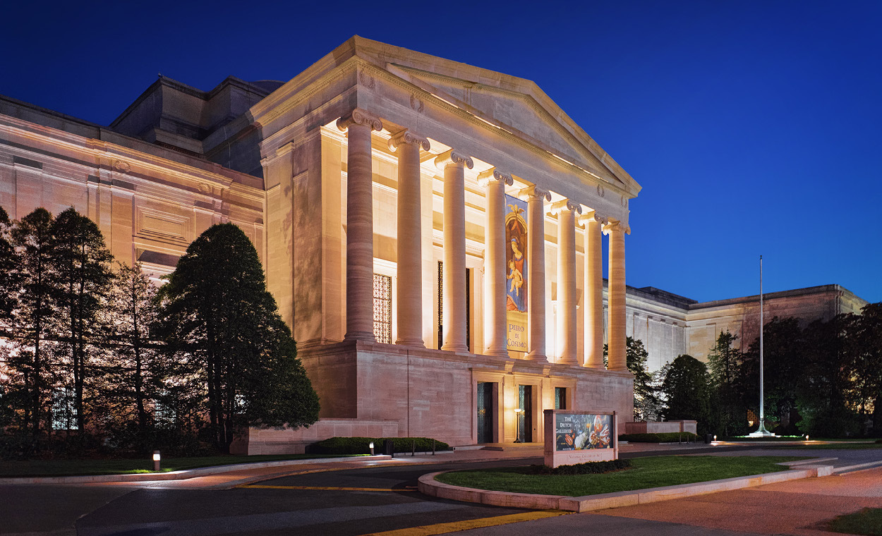 Large white building with columns illuminated at night.