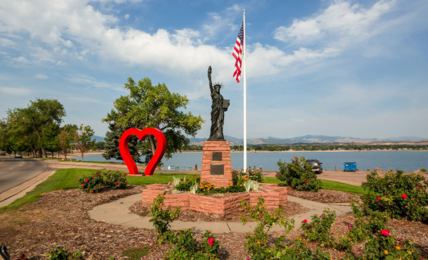 A miniature Statue of Liberty stands before a lake in Loveland, CO.