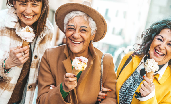 Three women smile as they eat ice cream cones.