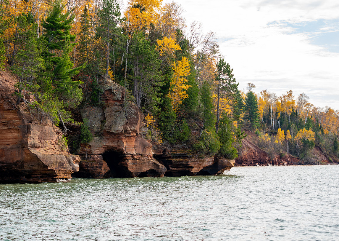 Yellow and green trees line a rocky river bed.