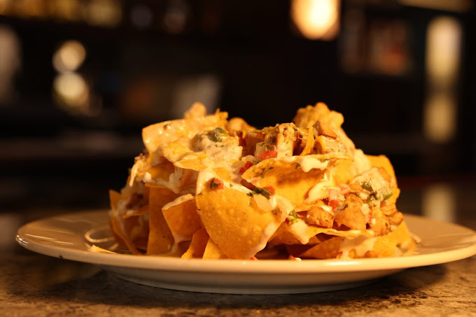 Nacho chips set on a plate with ambient lighting.