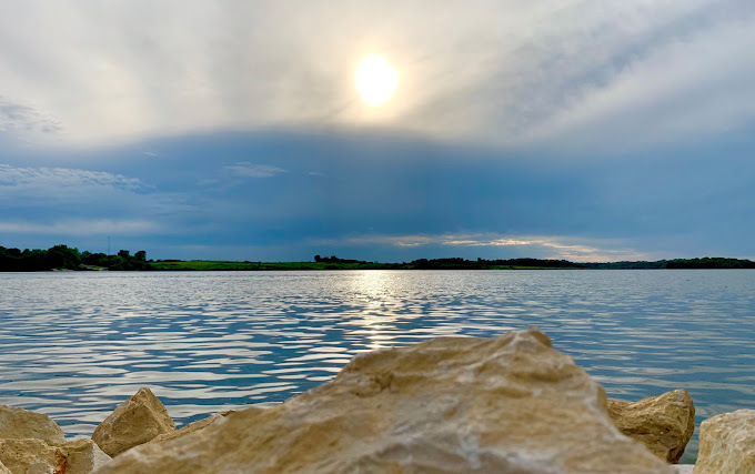 Lake view with rocks in the forefront of the image. It is a cloudy day.