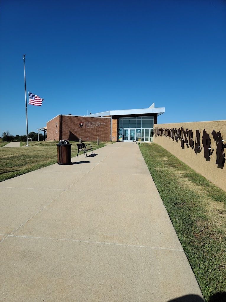 An outside view of a large museum building with a large glass window and an American flag out front.