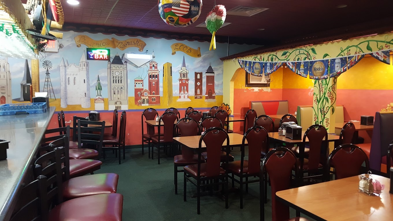 A view of a colorful dining room, a mural of a city covers the back wall, split orange and red on the other side.