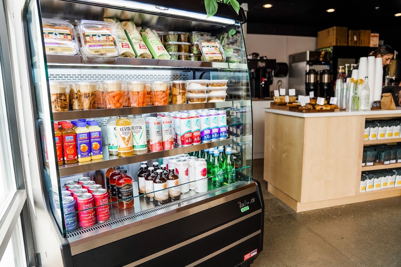 A landscape view of the fridge area of a café and checkout area.