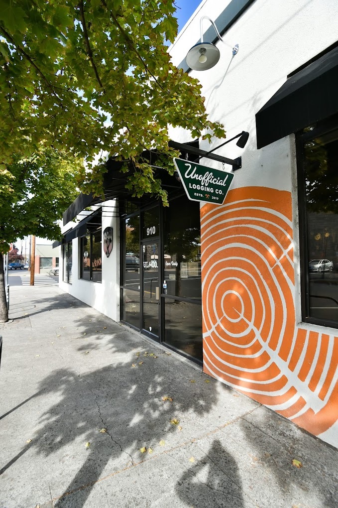 outside view of a business store front from the street, a white building with orange spiral design on the outside.