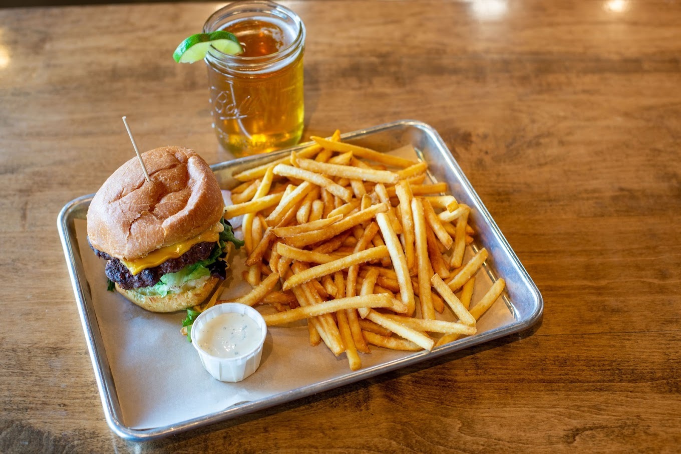 Metal serving tray consisting of a slider burger and a side of fries with a cup of ranch.