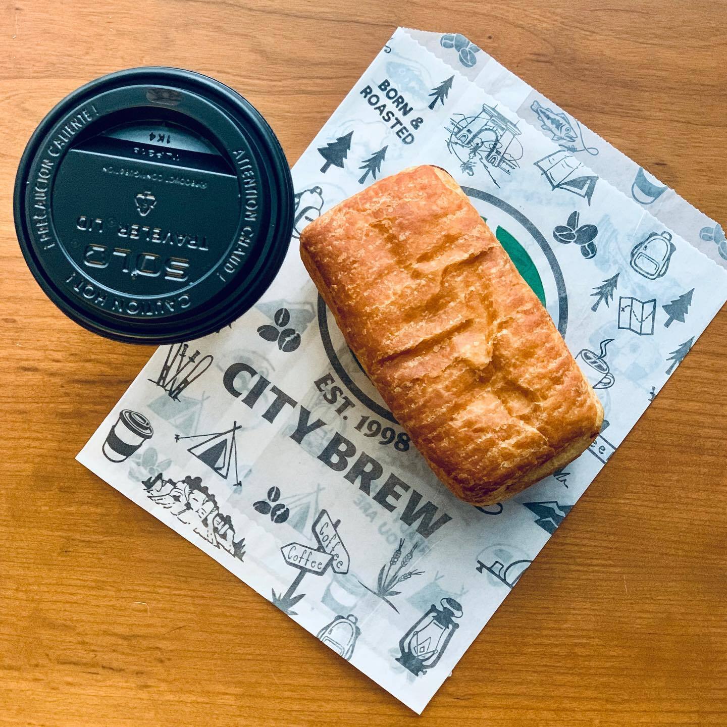 Close aerial view of a biscuit on a napkin and the top view of a hot to-go cup.