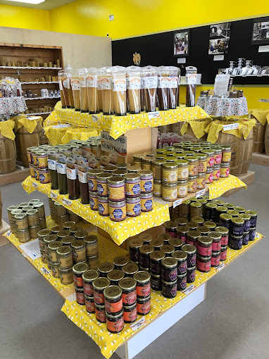 A yellow three-tiered stand filled with jars of honey products.