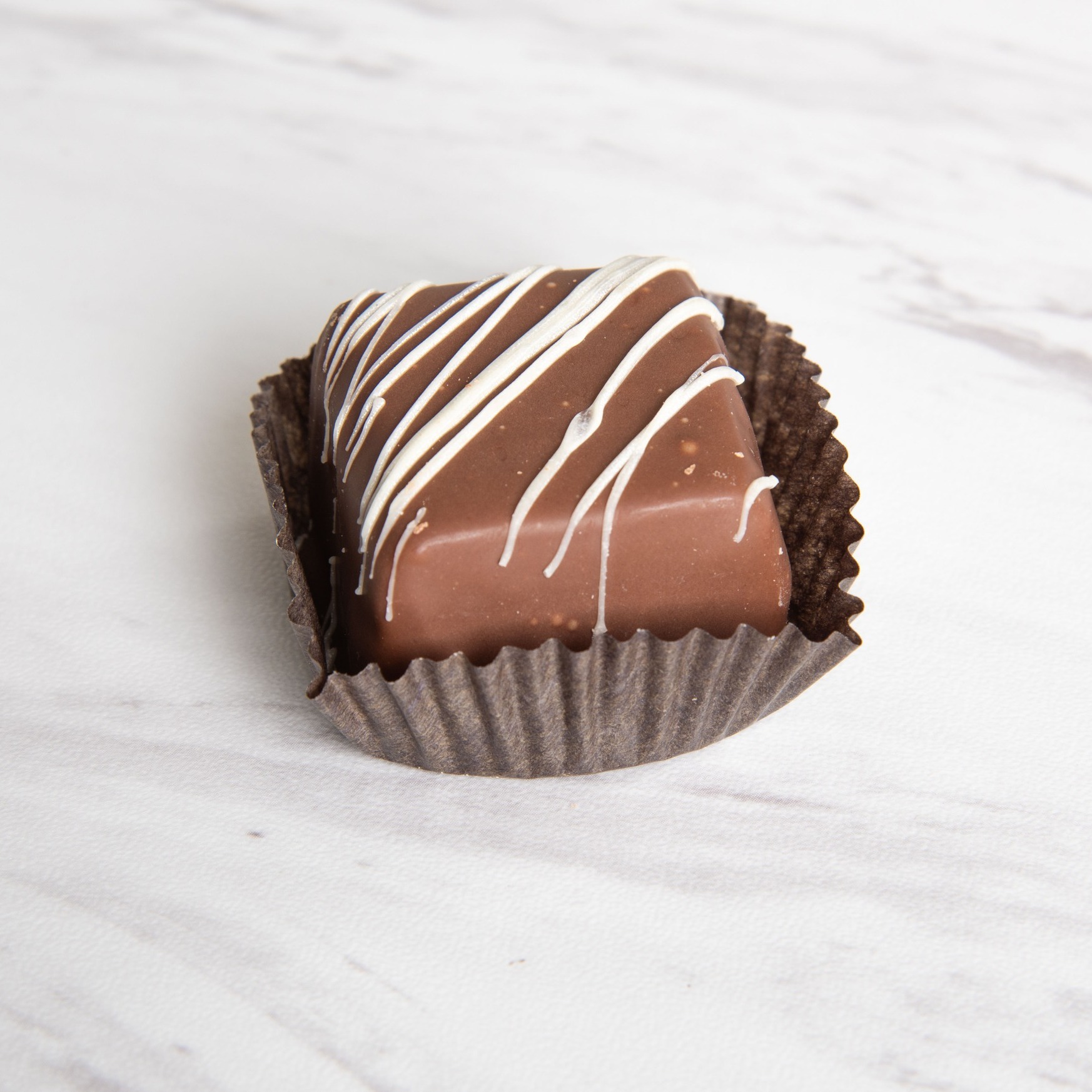 Close view of a chocolate with white drizzle in a cupcake baking liner.