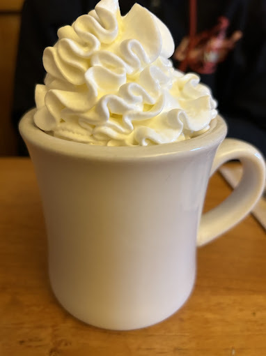 Drink in a white mug with a heavy amount of whipped cream on the top.