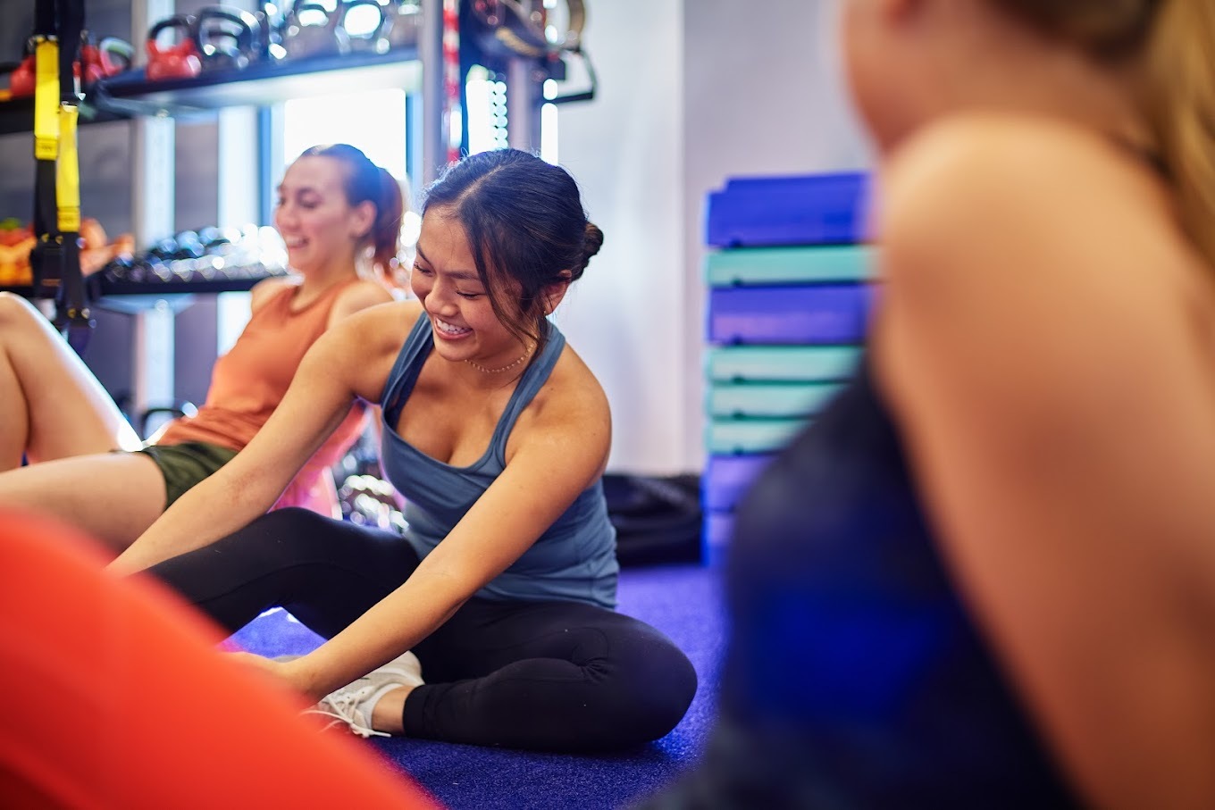 A view of a group of people stretching on the floor of a gym surrounded by gym equipment
