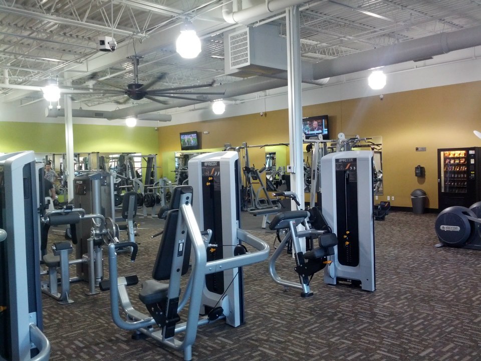 A room full of workout equipment, a green wall and a brown wall accent this room.