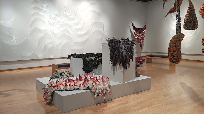 A large well light room with a large white block in the middle of the room with large pieces of art propped up on the white blocks.