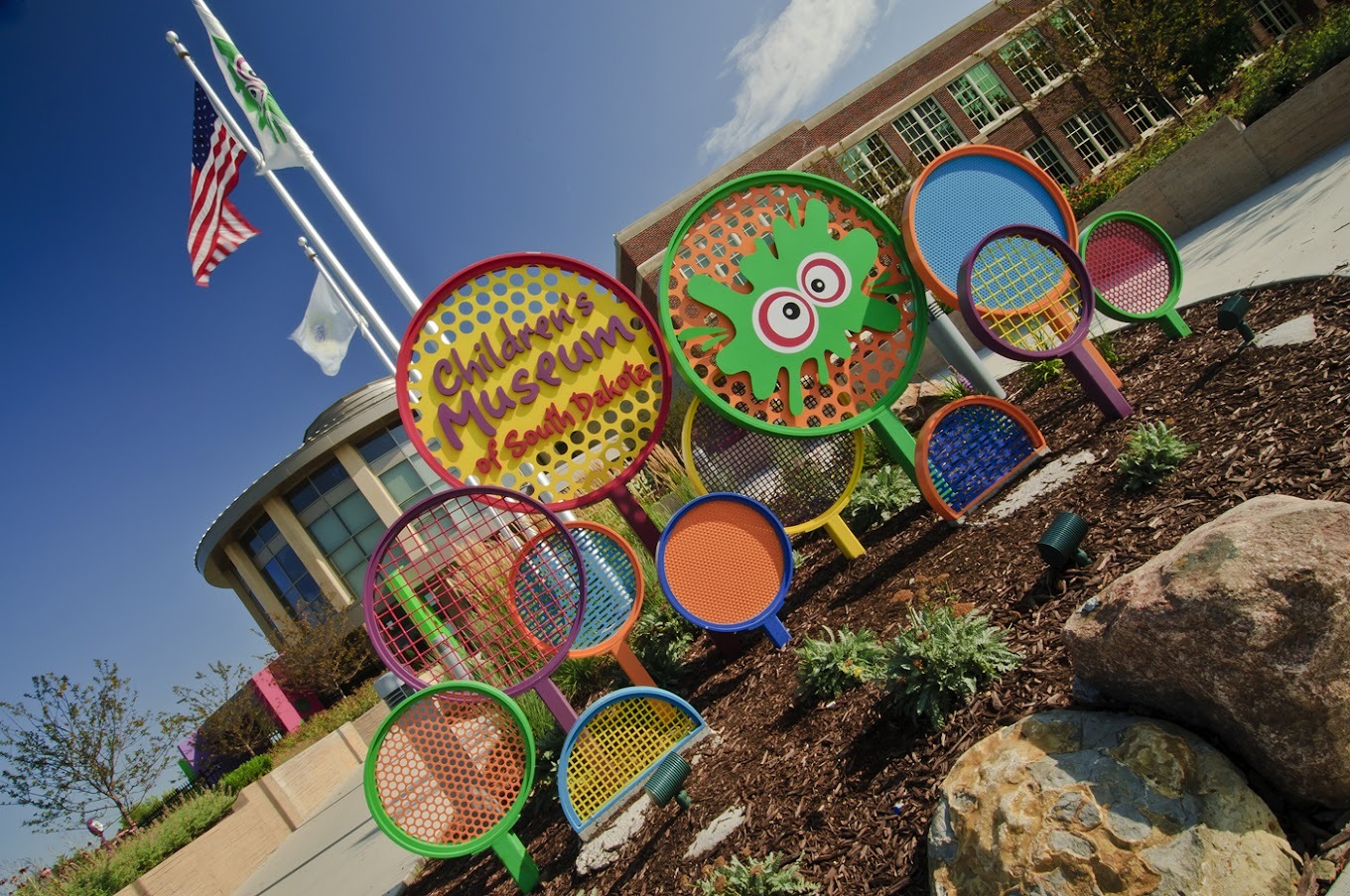 A view of a sign to a museum, a collage of colorful circles, splatter shapes, highlighting the museum name inside a red circle and a yellow border around the red text.