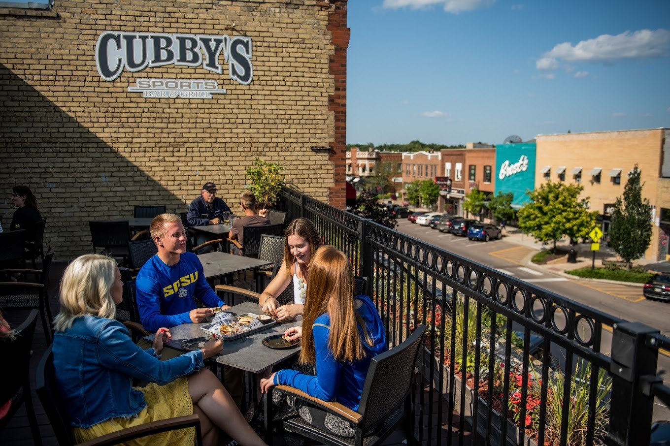 An outside view of a bar with a seating area on the roof, tables and chairs fill the space.