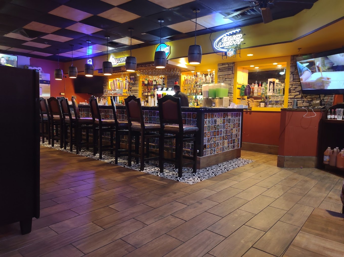 A view of bar, a dimly lit room with seats lining the bar.