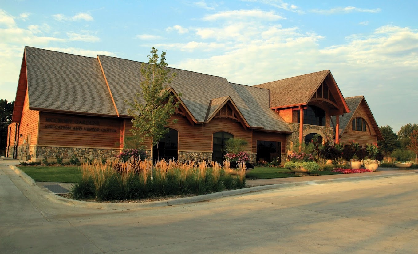 A large red building with lots of greenery and bushes out front of the large conservation building.