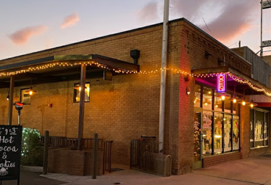 Corner view of a brown brick building with string lights strung across the window and door canopies.
