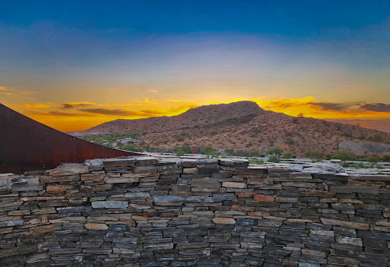 A brick wall covers the bottom half of the image. There is a hill view with a sunset in the image center.