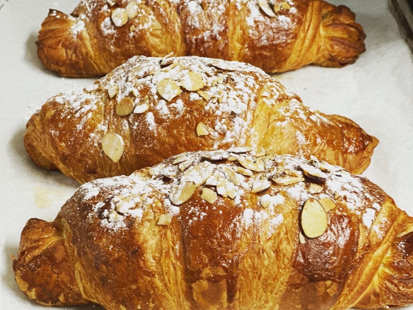 Close up view of croissants topped with nuts and flour.