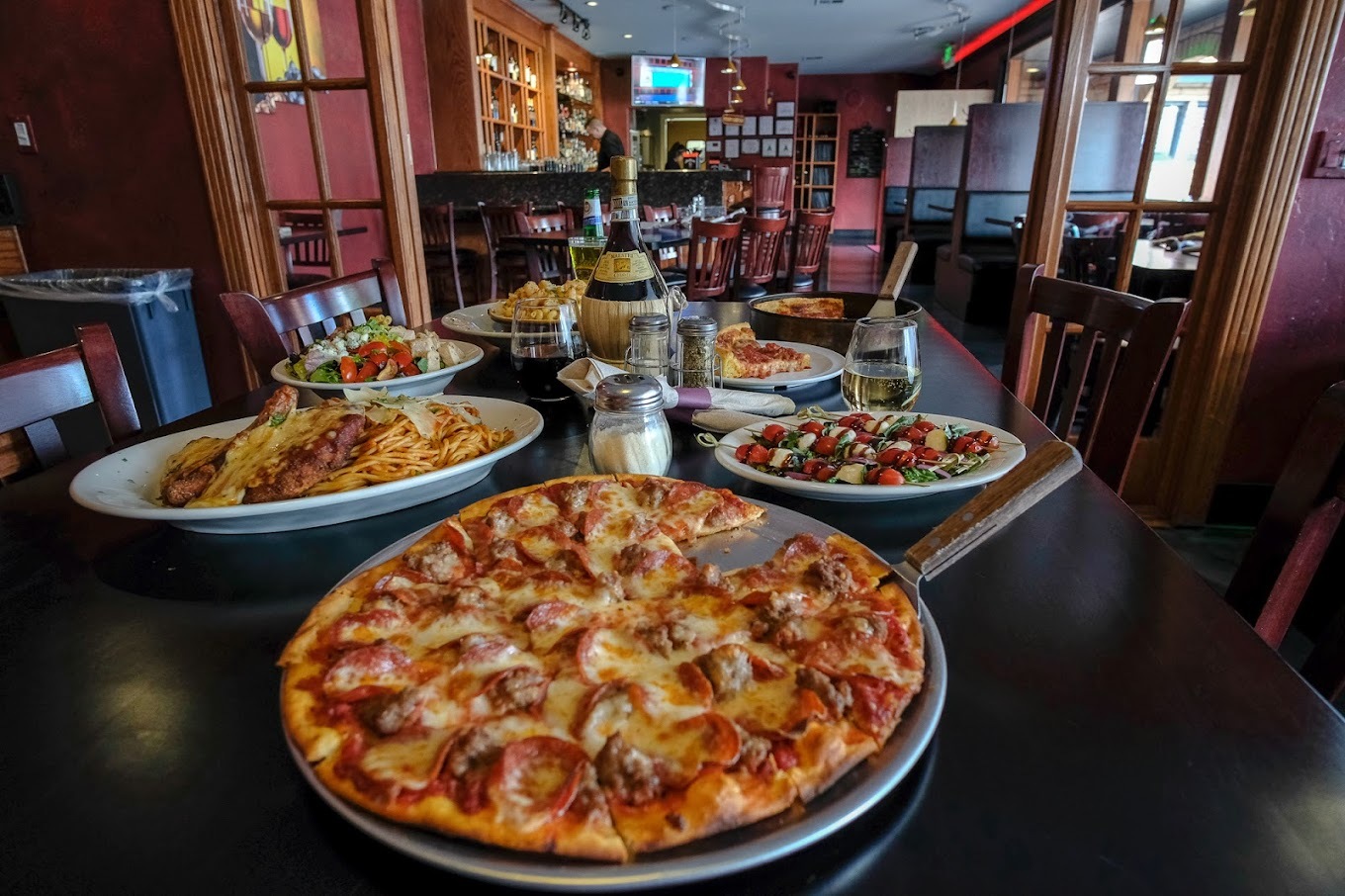 A table full of pizzas, topped with cheese meat and greens.