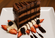 Slice of rich chocolate layer cake topped with chocolate drizzle and served with whipped cream, fresh strawberries, blackberries, and chocolate sauce on a white plate.
