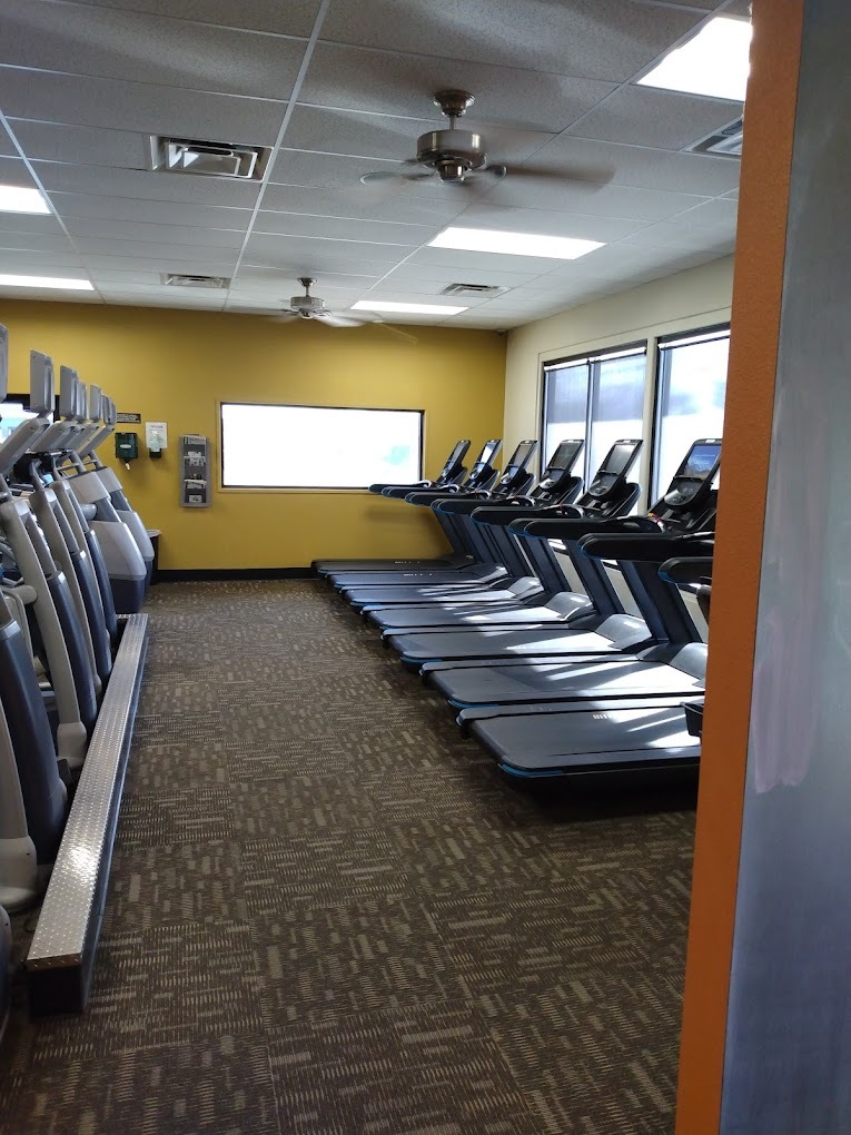 A room with yellow walls filled with treadmills
