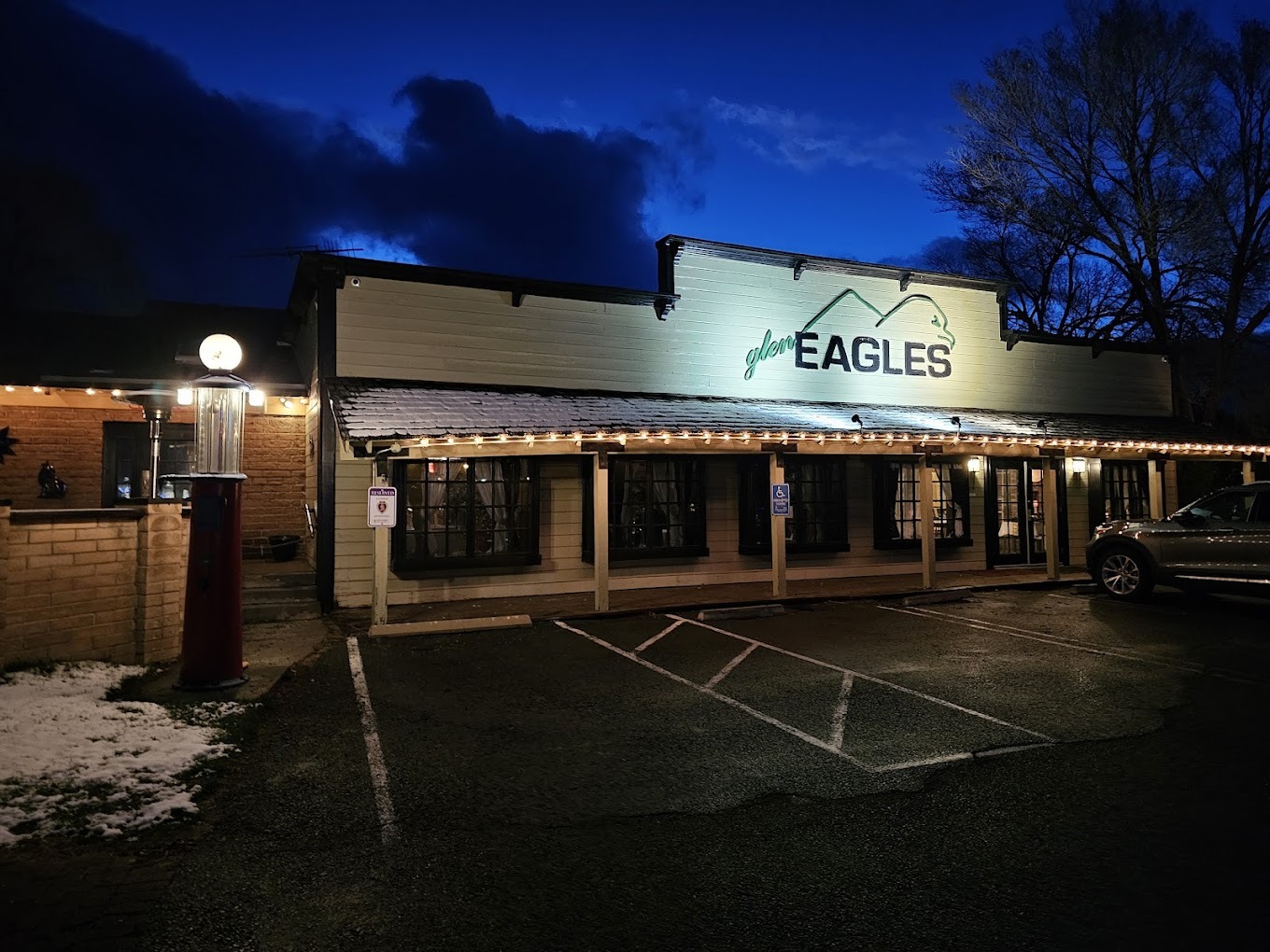An outside view of a saloon styled building with string lights on the awning, and a large sign above the door reading "Glen Eagles"