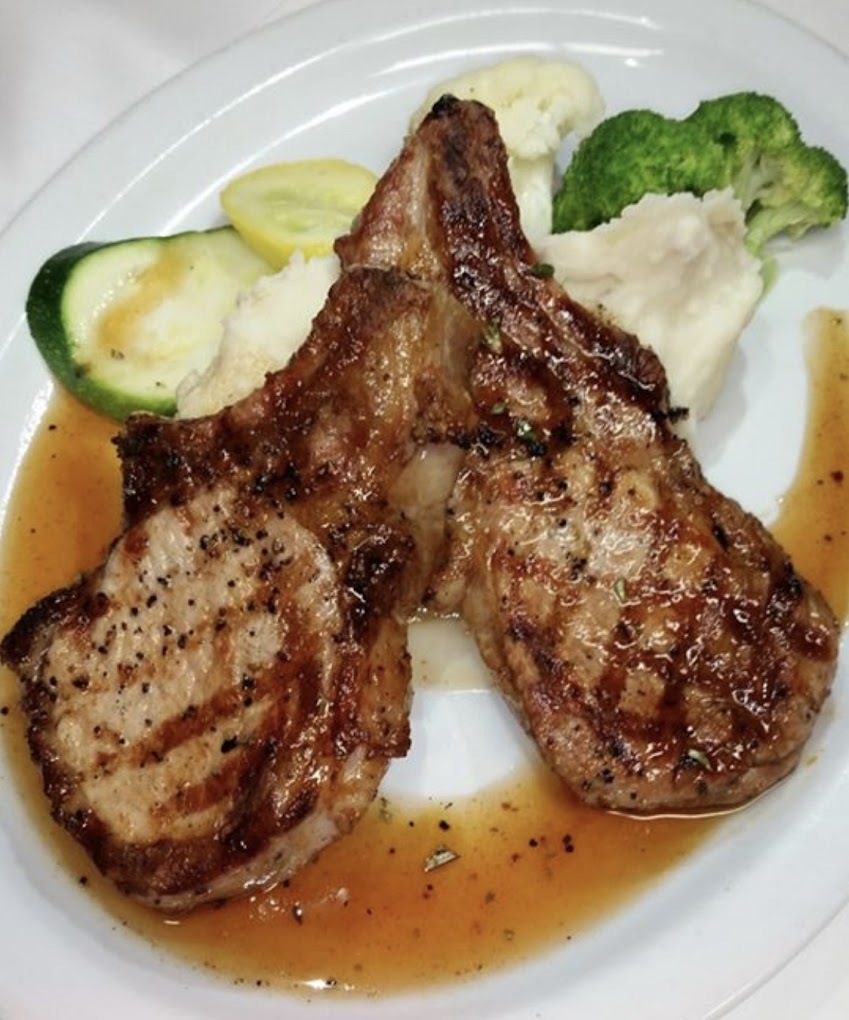 A white plate with a steak and grilled veggies on the side.