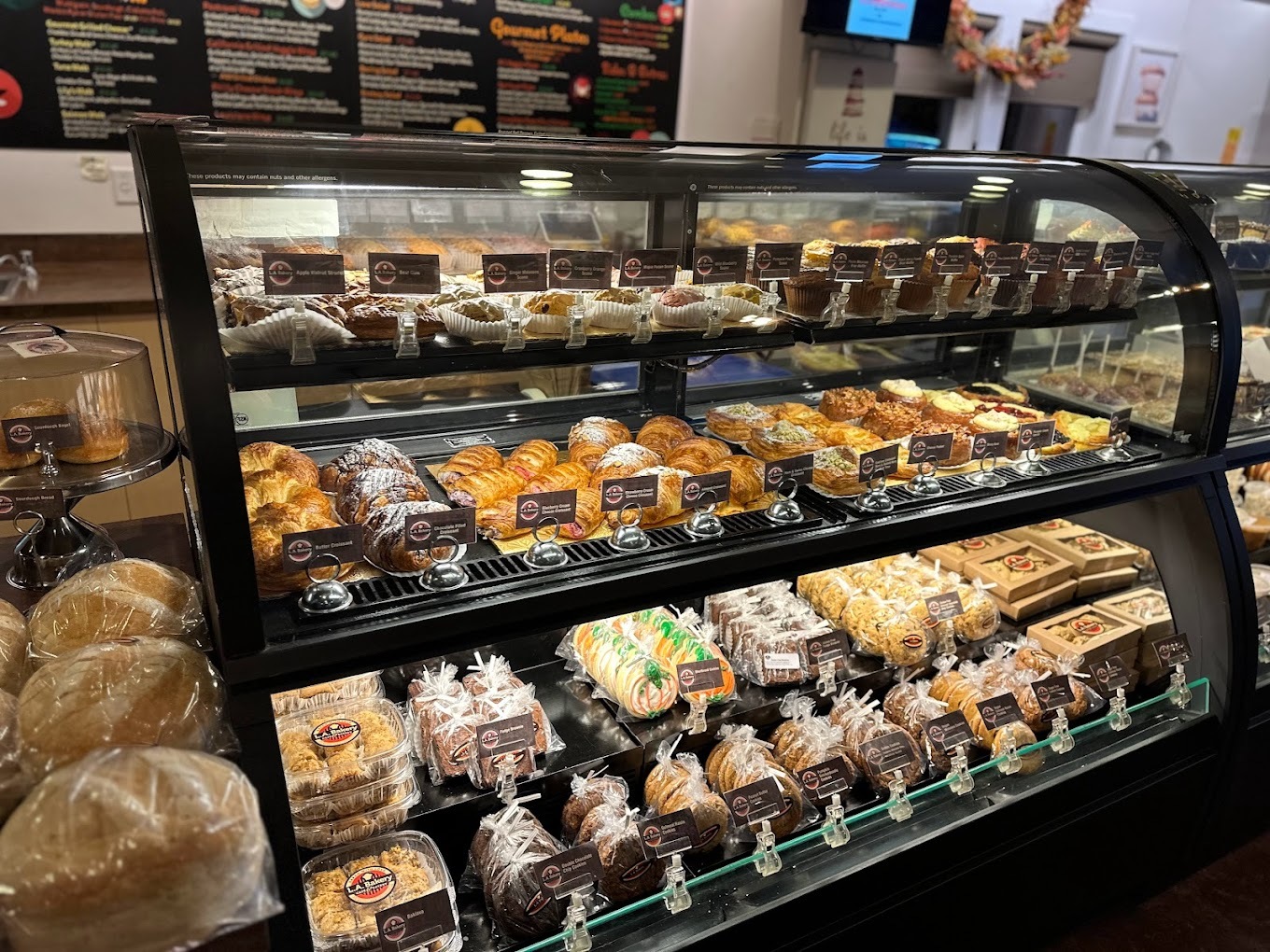 A view of a pastry display case filled with baked goods such as bread muffins, rolls, and cookies.