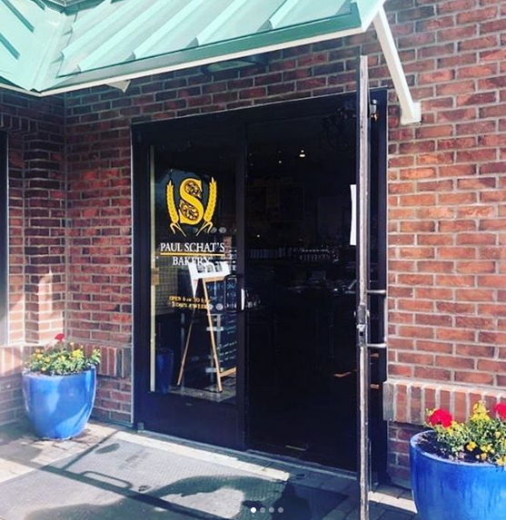 A brick building with a green awning, yellow lettering on the door.