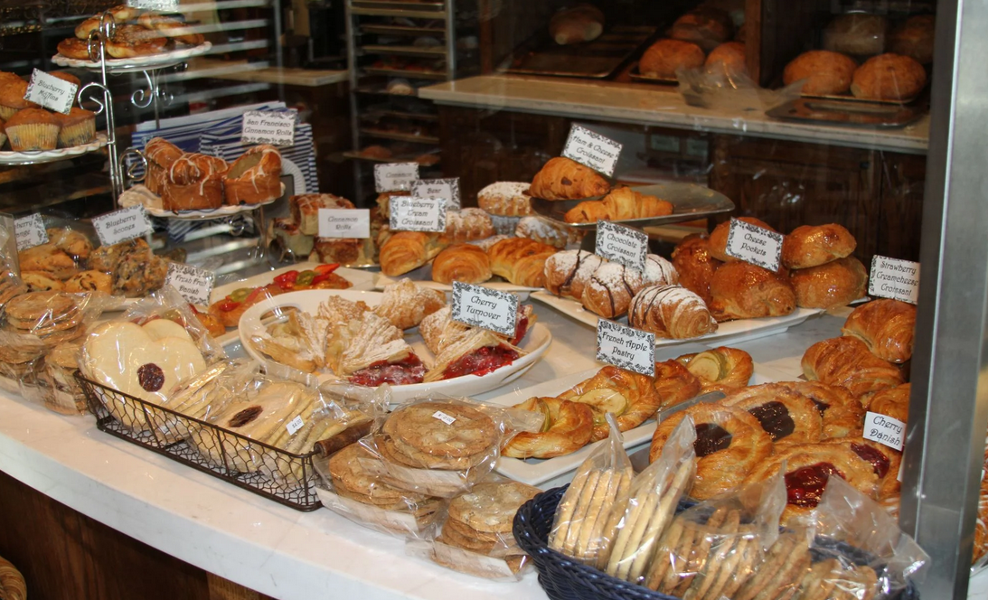 A table full of baskets and trays full of all kinds of baked goods- bread, cookies, rolls, scones, etc.