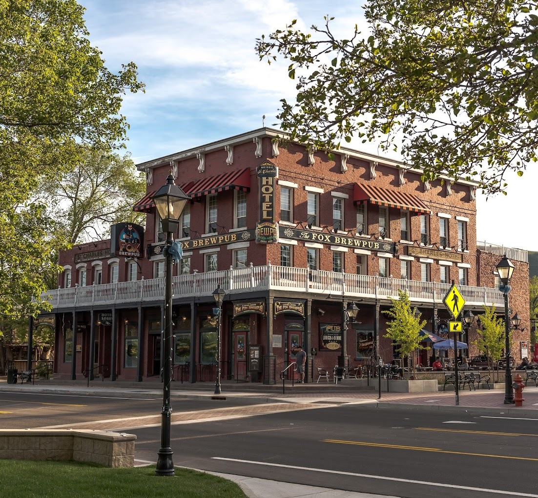 An outside view of a pub on a historical corner, a large red brick three story building