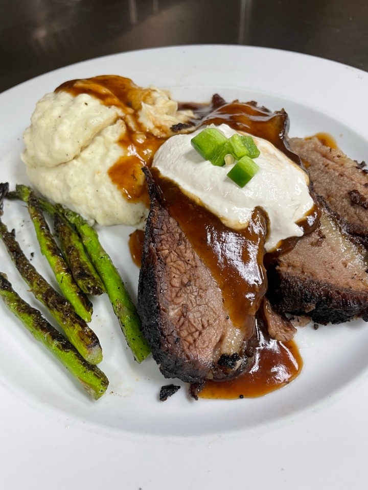 A white plate with meat, potatoes and asparagus.