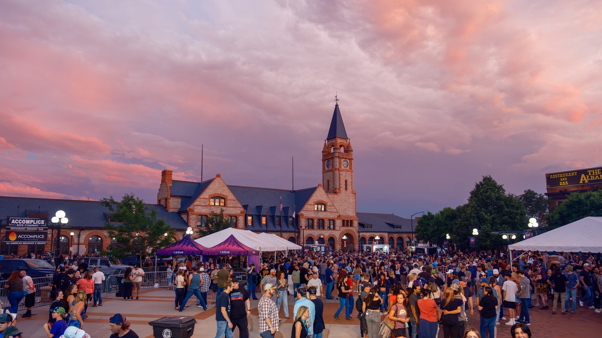 A view of a plaza with a beautiful sunset in purple red and pink in the background.