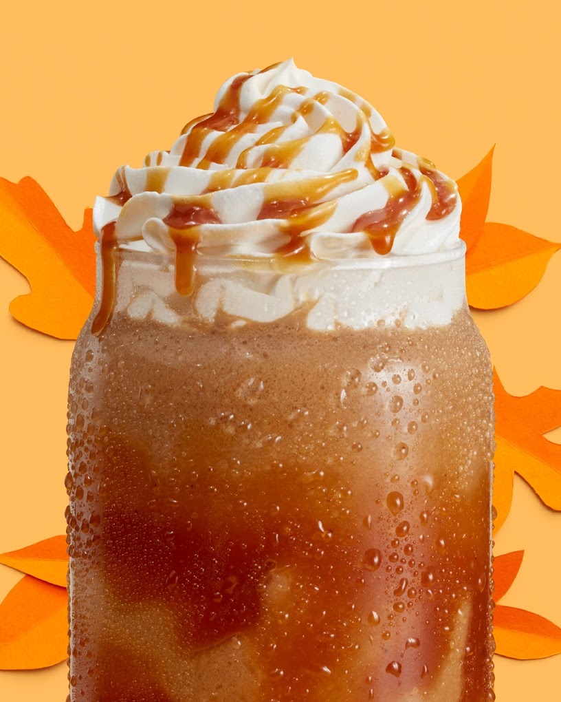 A view of a blended coffee drink, topped with whipped cream and caramel sauce.
