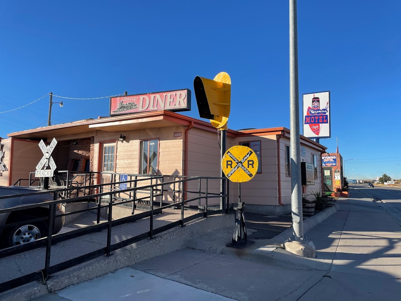 An outdoor view of a restaurant with an railroad themed signs out front, and a large white sign on top of the building with a train as the logo.